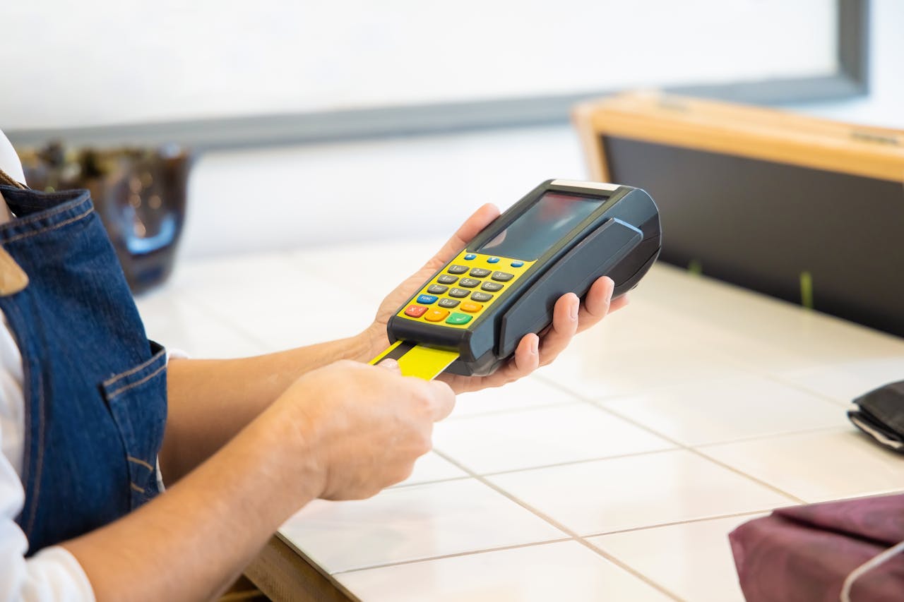 Close-up of hands operating a credit card POS machine in a commercial setting.